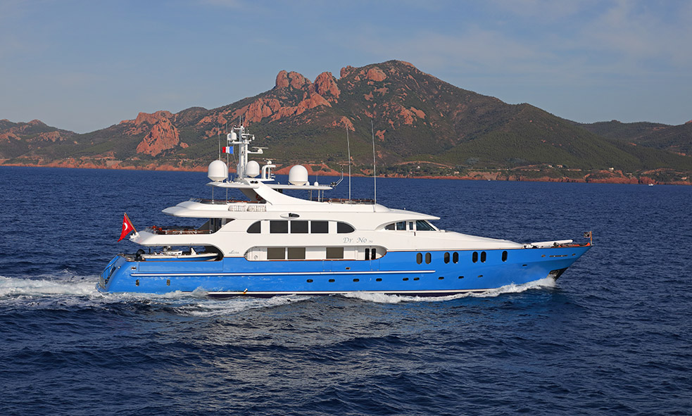 Superyacht DR NO NO cruising on beautiful blue sea with rugged mountain background